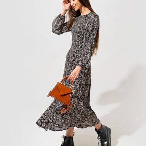 A model wearing a black and white polka dot dress paired with a brown handbag and black combat boots, showcasing a stylish outfit.